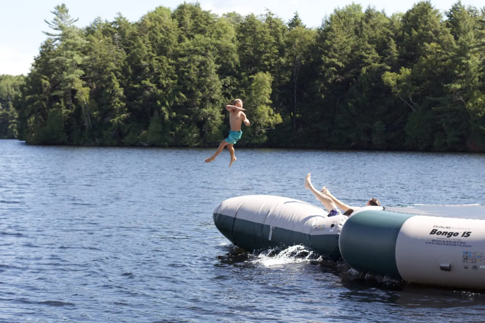 A person jumping off of an inflatable raft into the water.
