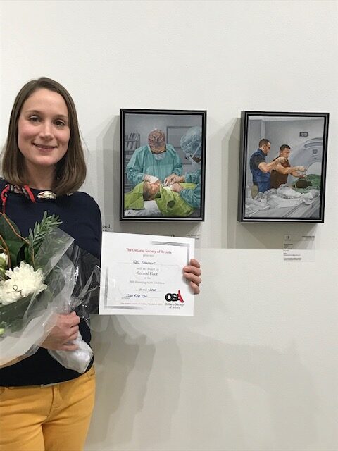 A woman holding flowers and a certificate in front of two framed pictures.