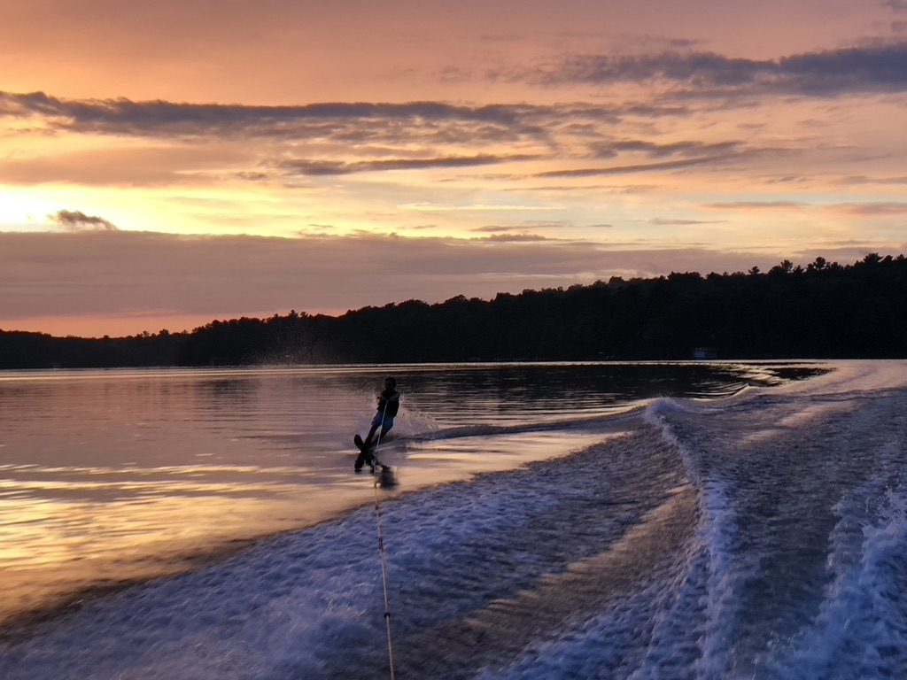 A person on water skis in the ocean at sunset.