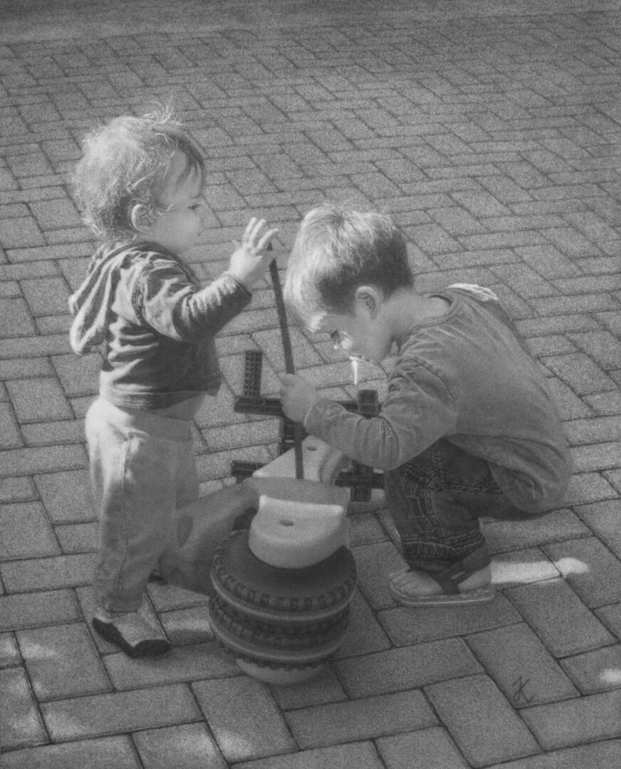 A boy and girl playing with an old fashioned toy.